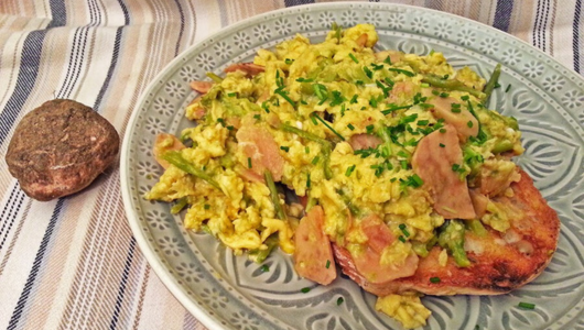 Scrambled eggs with herbs on toast beside a small round stone.