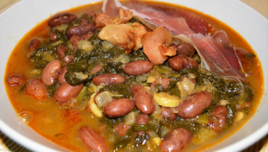 Bowl of bean soup with greens and meat pieces