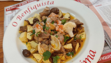 Dish with meat, clams, potatoes, and olives on a white plate.