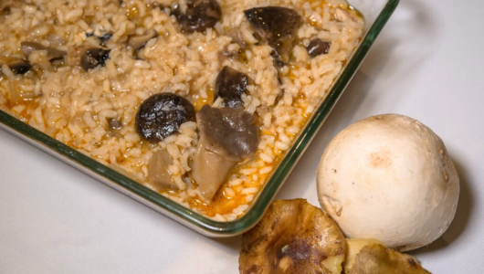 Mushroom rice dish in a glass tray with a mushroom and fried plantain on the side.
