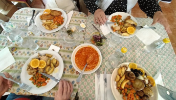 Four plates of food with vegetables and oranges on a table.