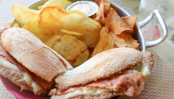 Pan with sandwiches and chips, small sauce container in the center.