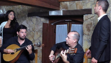 Four musicians performing indoors, two playing string instruments, two standing and watching.