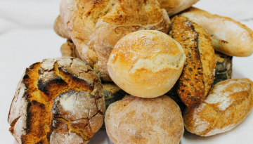 Assorted rustic bread rolls piled on a white surface.