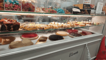 Display case with assorted cakes, pastries, and colorful candies in a bakery.