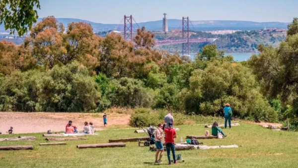 People relaxing in a park with a distant bridge and statue in the background.