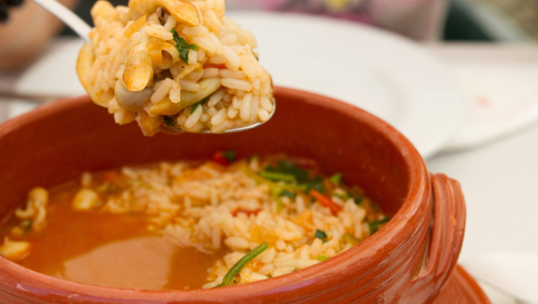 Spoon lifting seasoned rice from a bowl of broth.