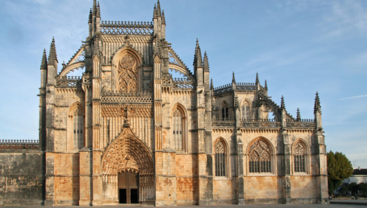 Gothic-style cathedral with ornate spires and large arches under a clear blue sky.