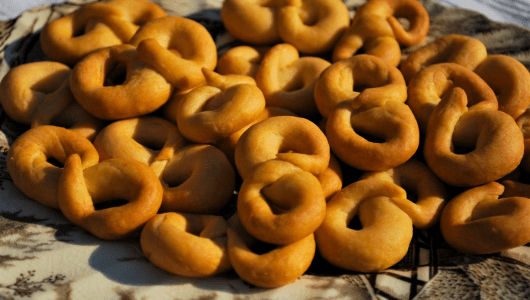 Pile of golden brown baked ring-shaped cookies on a cloth.
