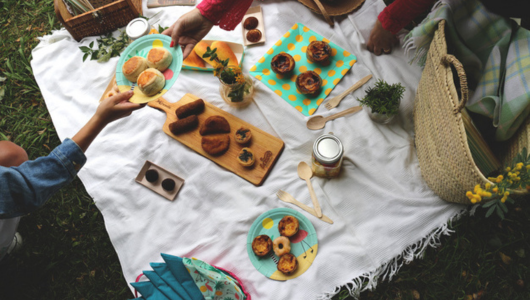 Top view of picnic setup with food on a white blanket.