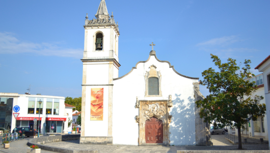 Small white church with bell tower and ornate door.