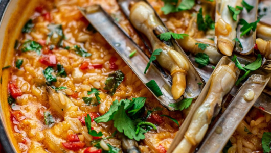 Seafood rice dish with razor clams and garnish.