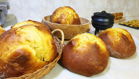Assorted freshly baked loaves of golden-brown bread on a kitchen counter.