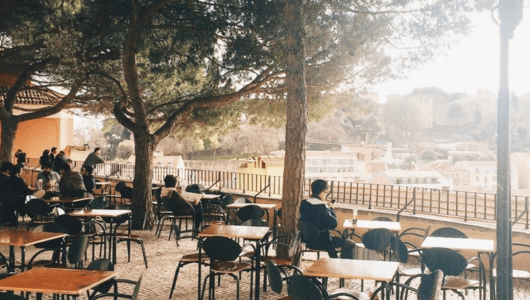Outdoor cafe with tables, chairs, and a view of city buildings