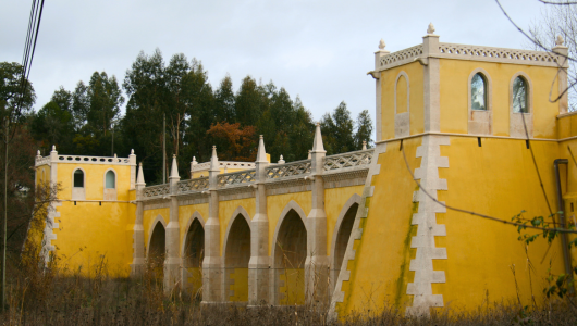 Yellow castle-like building with arched windows and ornate crenellations.