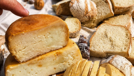 Variety of cheeses and sliced bread on a cloth surface.
