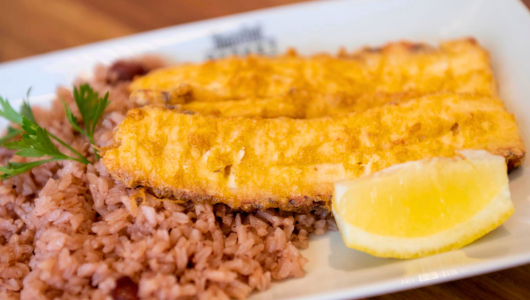 Fish fillet and rice on a plate with a lemon wedge