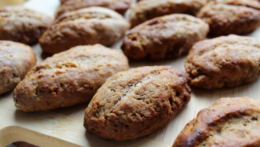 Close-up of several brown, baked pastries on a wooden board.