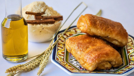 Two pastries on a colorful plate with oil, cinnamon, and wheat.