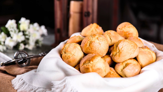 Basket of freshly baked bread rolls on a white cloth.