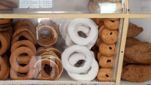 Display case with assorted baked goods, including rings and oval pastries.