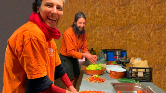 Two people preparing vegetables in a kitchen, both wearing orange shirts.