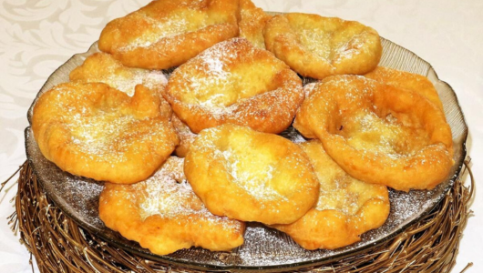 Plate of fried dough pastries topped with powdered sugar.