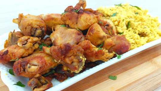 Plate of fried chicken pieces and scrambled eggs garnished with herbs.