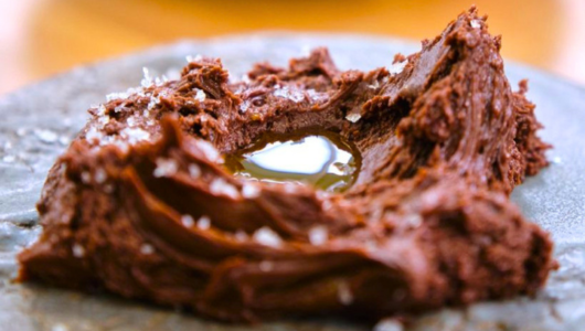 Close-up of a chocolate dessert with a glossy center on a dark plate.