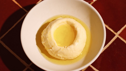 Mashed potatoes shaped in a bowl with melted butter on a plate.