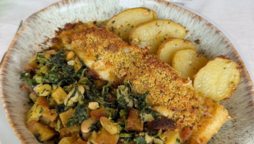 Baked fish with herbs and breadcrumbs, roasted potatoes, and vegetable mix on a plate.