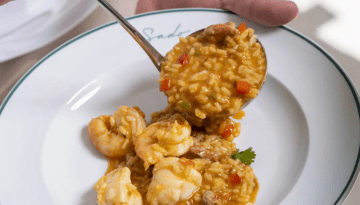 Seafood risotto with shrimp on a white plate, garnished with parsley.