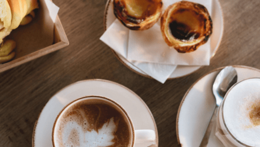Cappuccinos and pastries on a wooden table.