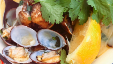 Clams with lemon wedge and cilantro garnish.