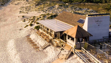 Beachside restaurant with outdoor seating on sandy dunes.
