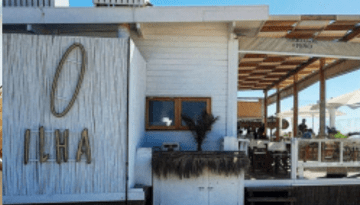 Outdoor beach restaurant with wooden decor and people dining.