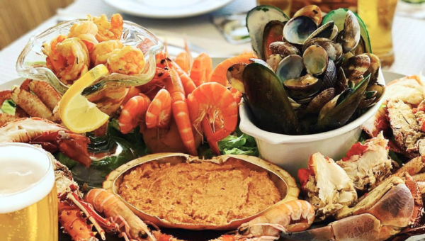 A seafood platter with shrimp, mussels, clams, and crab, garnished with lemon wedges and greens.
