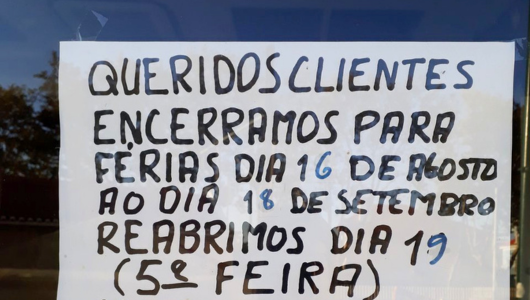 Sign in Portuguese announcing store closure for vacation from Aug 16 to Sep 18, reopening on Sep 19.