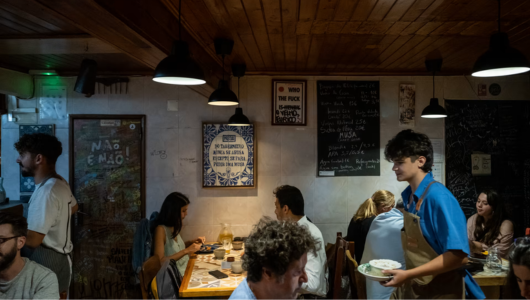 Crowded restaurant with diners eating and staff serving food.