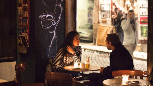 Two people talking in a cozy cafe with candlelight.