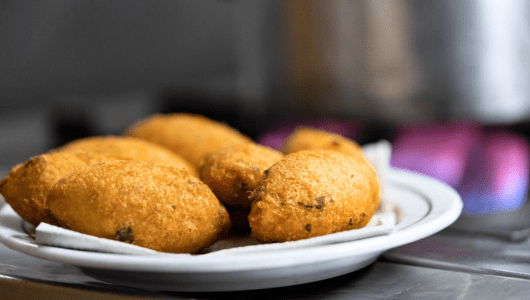 Plate of fried pastries on a kitchen counter with stove in background.