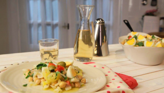 Plate of salad with glass and carafe on white table.