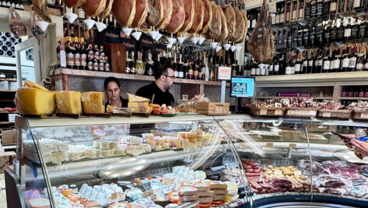 Deli with meats, cheeses, and staff behind the counter in a busy shop.