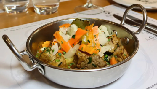 Mixed vegetables and meat in a metal dish on a table setting.
