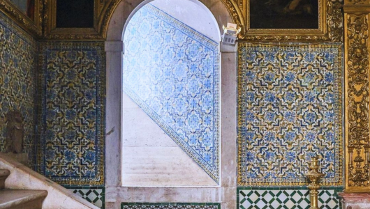 Ornate interior with tiled walls and an arched doorway leading to stairs.