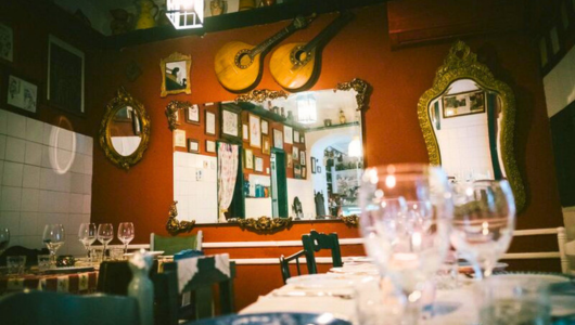 Cozy restaurant with mirrors, guitars, and glasses on set tables.