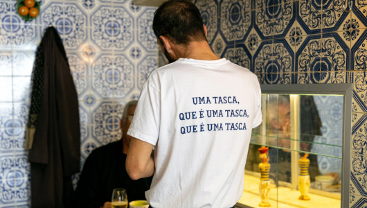 Man in a white shirt with text in a tiled restaurant setting.