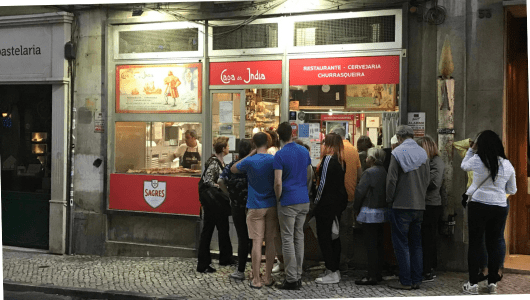 People standing in line outside a restaurant at night.