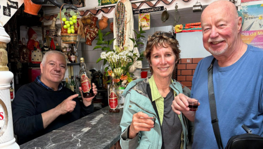 Three people smiling, holding drinks in a bar with colorful decor.