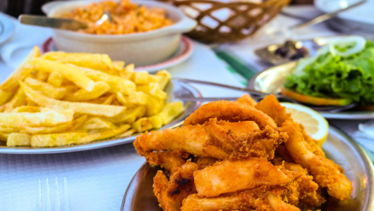 Plates of fries, fried chicken, and salad on a table.